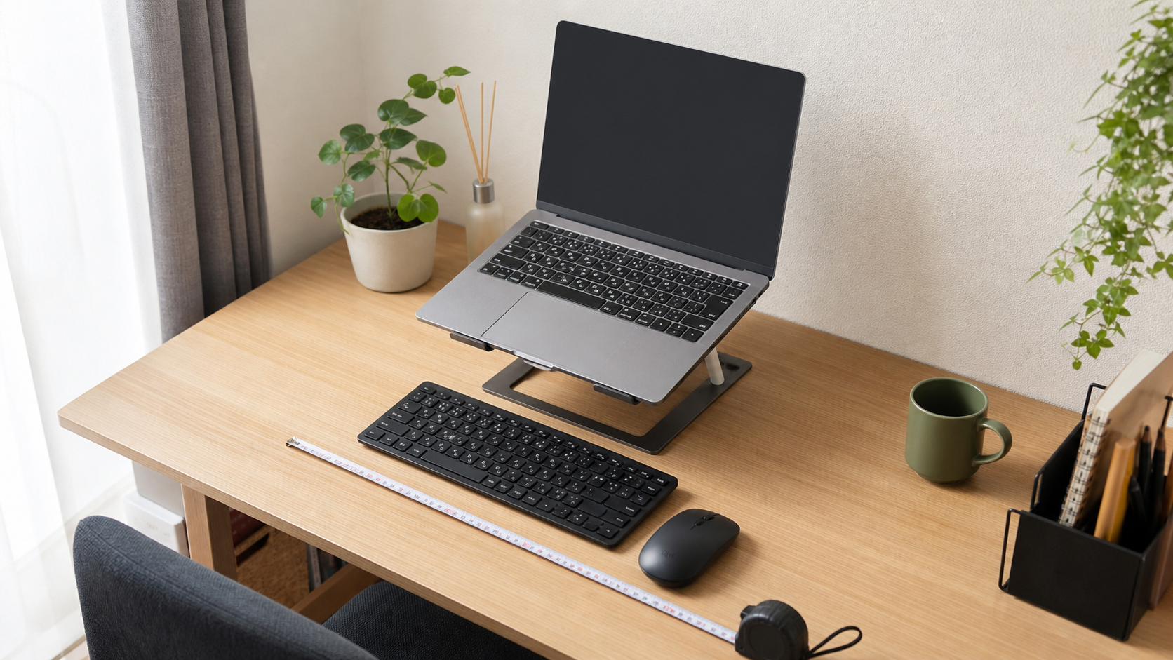 ノートパソコンスタンドを置く前に机の奥行きとキーボード位置を測っているイメージ